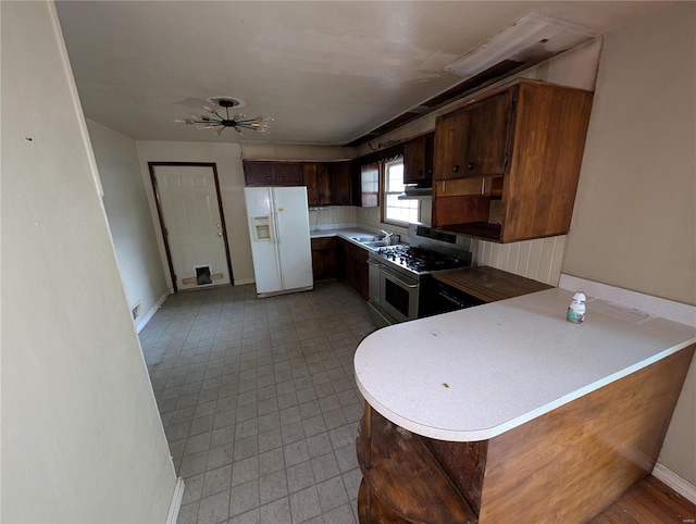 kitchen featuring kitchen peninsula, gas stove, white fridge with ice dispenser, ceiling fan, and sink