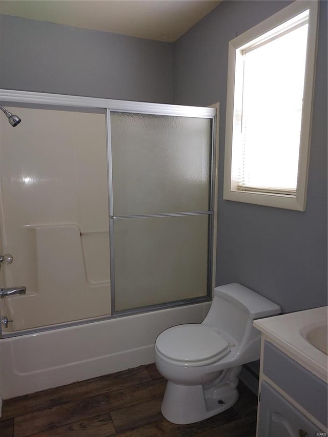 full bathroom featuring shower / bath combination with glass door, hardwood / wood-style flooring, toilet, and vanity