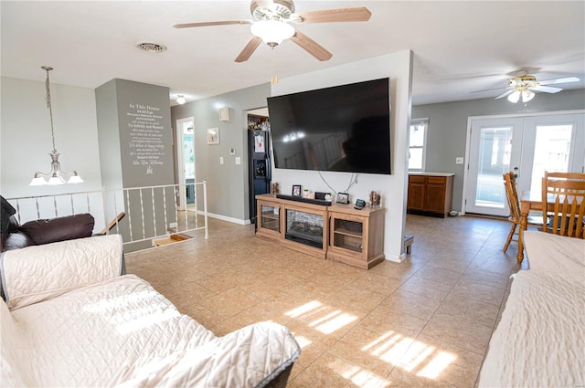 living room with french doors and ceiling fan with notable chandelier