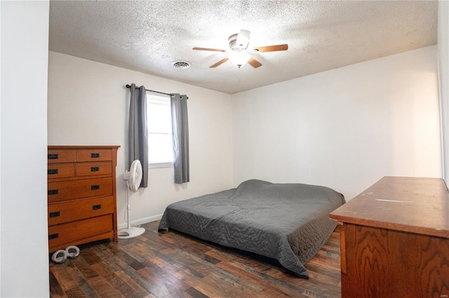 bedroom featuring dark wood-type flooring, ceiling fan, and a textured ceiling