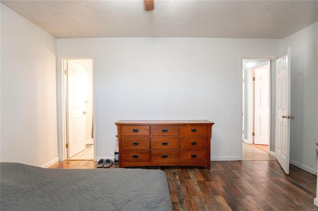 bedroom with ceiling fan, dark wood-type flooring, and a textured ceiling