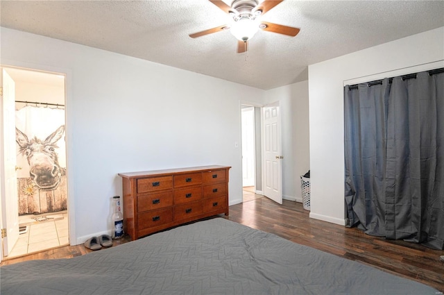 bedroom with ceiling fan, ensuite bath, dark hardwood / wood-style floors, and a textured ceiling