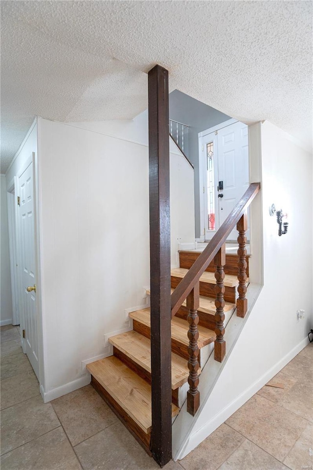 stairs featuring tile patterned floors and a textured ceiling