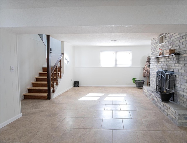 basement with a fireplace, a textured ceiling, and light tile patterned flooring