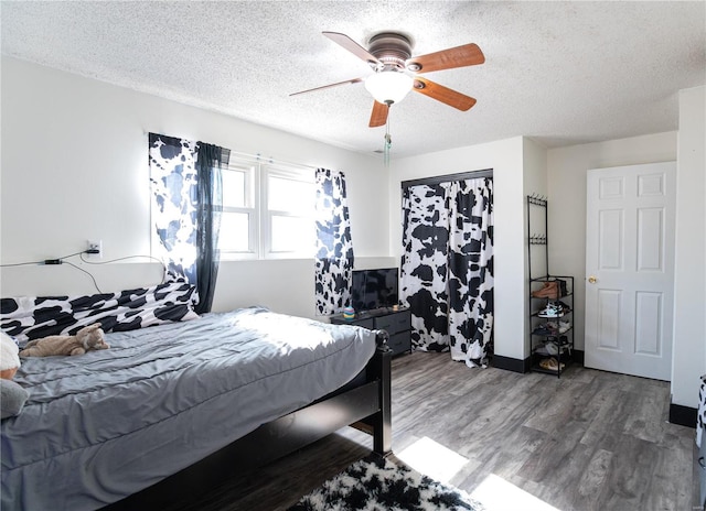 bedroom with ceiling fan, dark wood-type flooring, and a textured ceiling