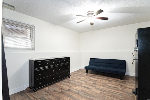 living area featuring wood-type flooring, ceiling fan, and a textured ceiling