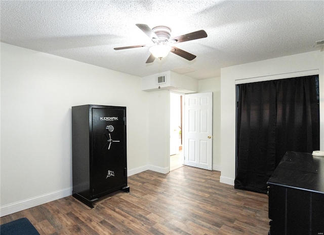 bedroom with ceiling fan, dark wood-type flooring, and a textured ceiling