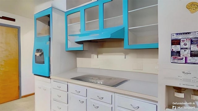 kitchen with black electric cooktop, white cabinetry, and water heater