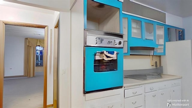 kitchen with fridge, white cabinetry, and oven