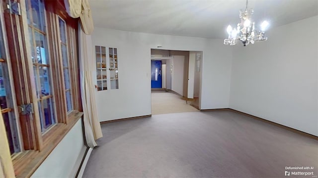 carpeted empty room featuring an inviting chandelier