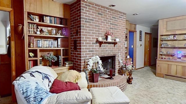 carpeted living room with wood walls and a brick fireplace