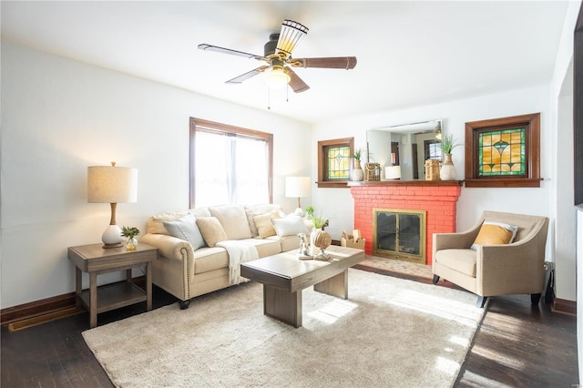 living room featuring a brick fireplace, dark wood-type flooring, and ceiling fan