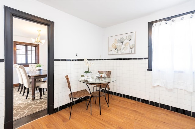 dining space with an inviting chandelier, tile walls, and wood-type flooring