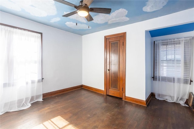 unfurnished bedroom with ceiling fan, dark hardwood / wood-style floors, and multiple windows