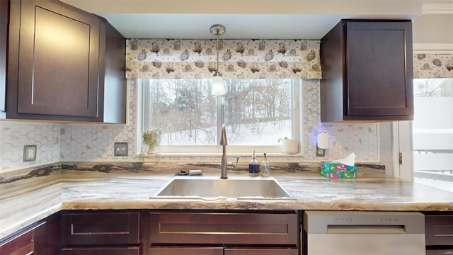 kitchen featuring tasteful backsplash, white dishwasher, dark brown cabinets, hanging light fixtures, and sink