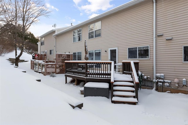 snow covered back of property featuring a deck