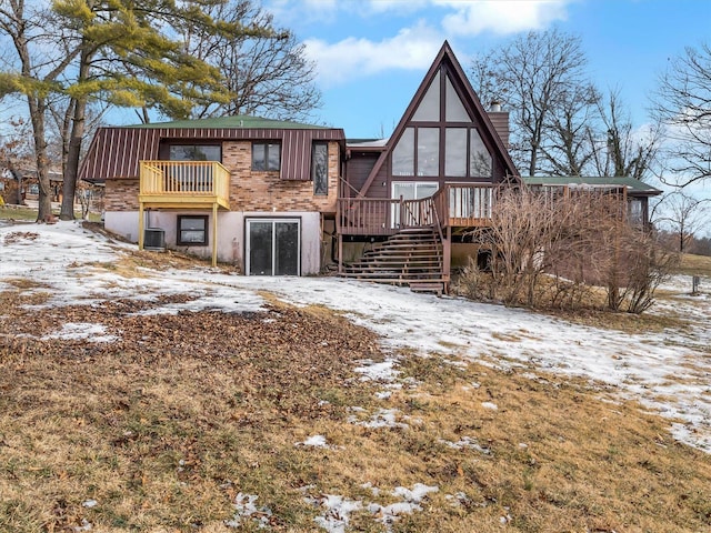 snow covered house with central air condition unit and a deck