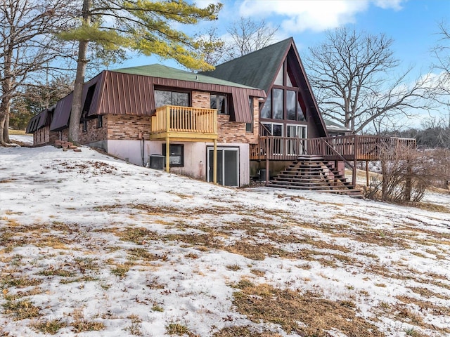 snow covered property with cooling unit and a wooden deck