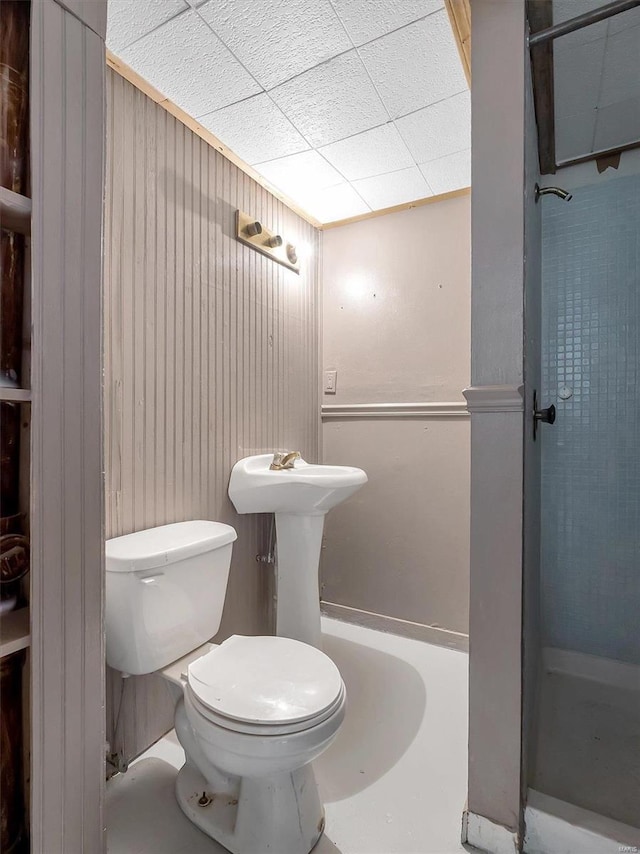 bathroom with walk in shower, toilet, and wood walls