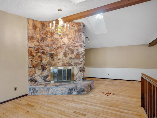 unfurnished living room with wood-type flooring, a stone fireplace, heating unit, and lofted ceiling with skylight