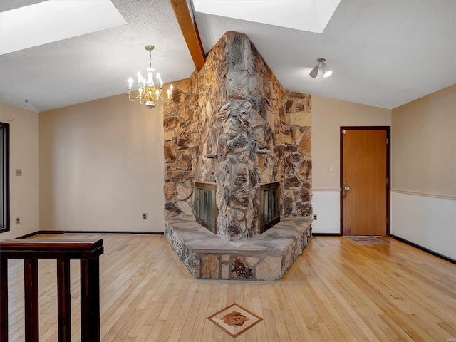 living room with a stone fireplace, light wood-type flooring, a textured ceiling, and lofted ceiling with skylight