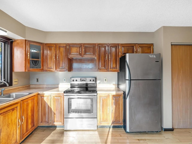 kitchen featuring appliances with stainless steel finishes, sink, light hardwood / wood-style flooring, and a textured ceiling