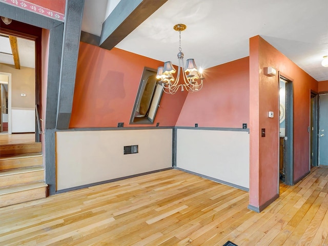 unfurnished dining area with beam ceiling, light hardwood / wood-style flooring, and a chandelier