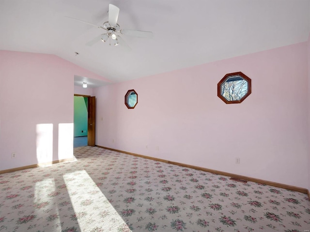 empty room with ceiling fan, vaulted ceiling, and light carpet