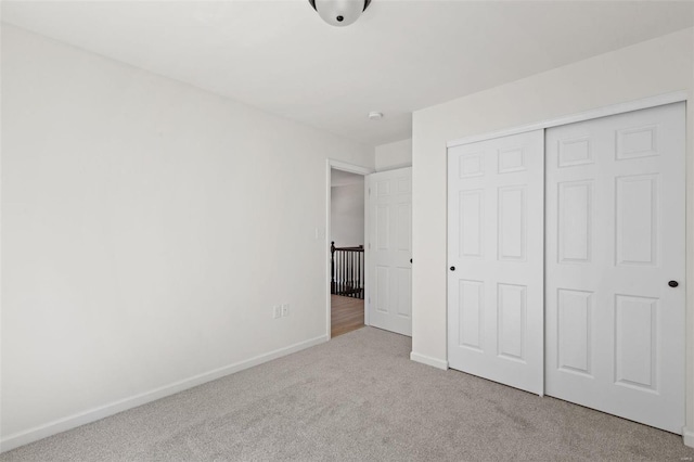 unfurnished bedroom featuring a closet and light colored carpet