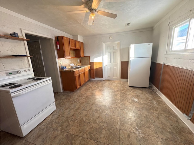 kitchen featuring white appliances, ceiling fan, backsplash, and wood walls