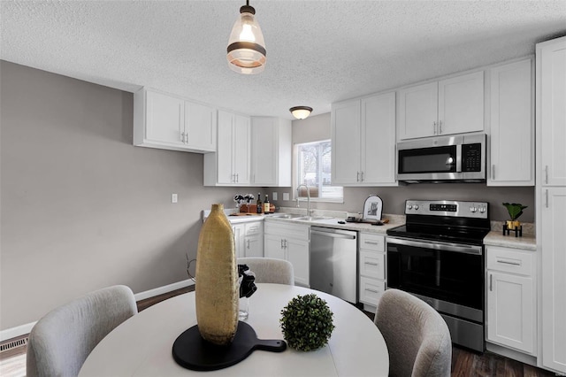 kitchen featuring sink, pendant lighting, stainless steel appliances, and white cabinetry