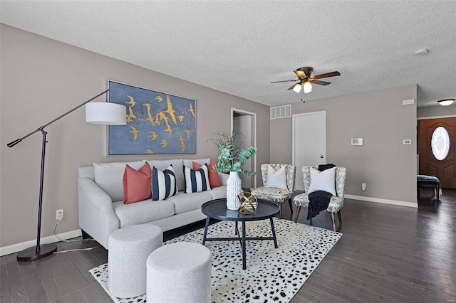 living room featuring ceiling fan, dark wood-type flooring, and a textured ceiling