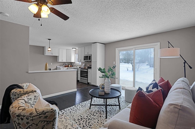 living room with a textured ceiling, dark wood-type flooring, sink, and ceiling fan