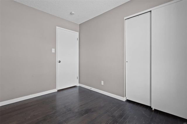 unfurnished bedroom with a textured ceiling, a closet, and dark hardwood / wood-style flooring