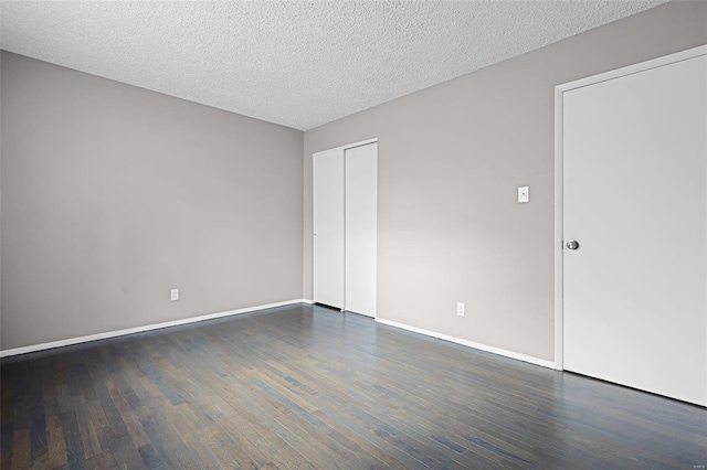 unfurnished room with a textured ceiling and dark hardwood / wood-style flooring