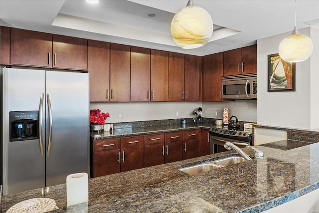 kitchen featuring dark stone countertops, hanging light fixtures, sink, and appliances with stainless steel finishes