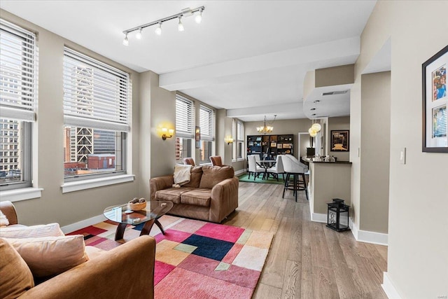 living room featuring a notable chandelier, wood-type flooring, and rail lighting