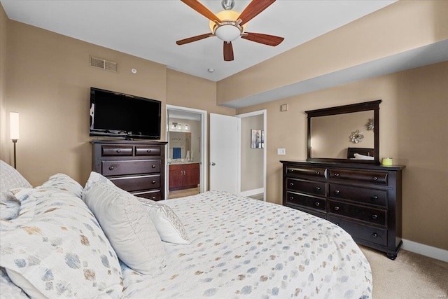 bedroom featuring light colored carpet, ceiling fan, and ensuite bathroom