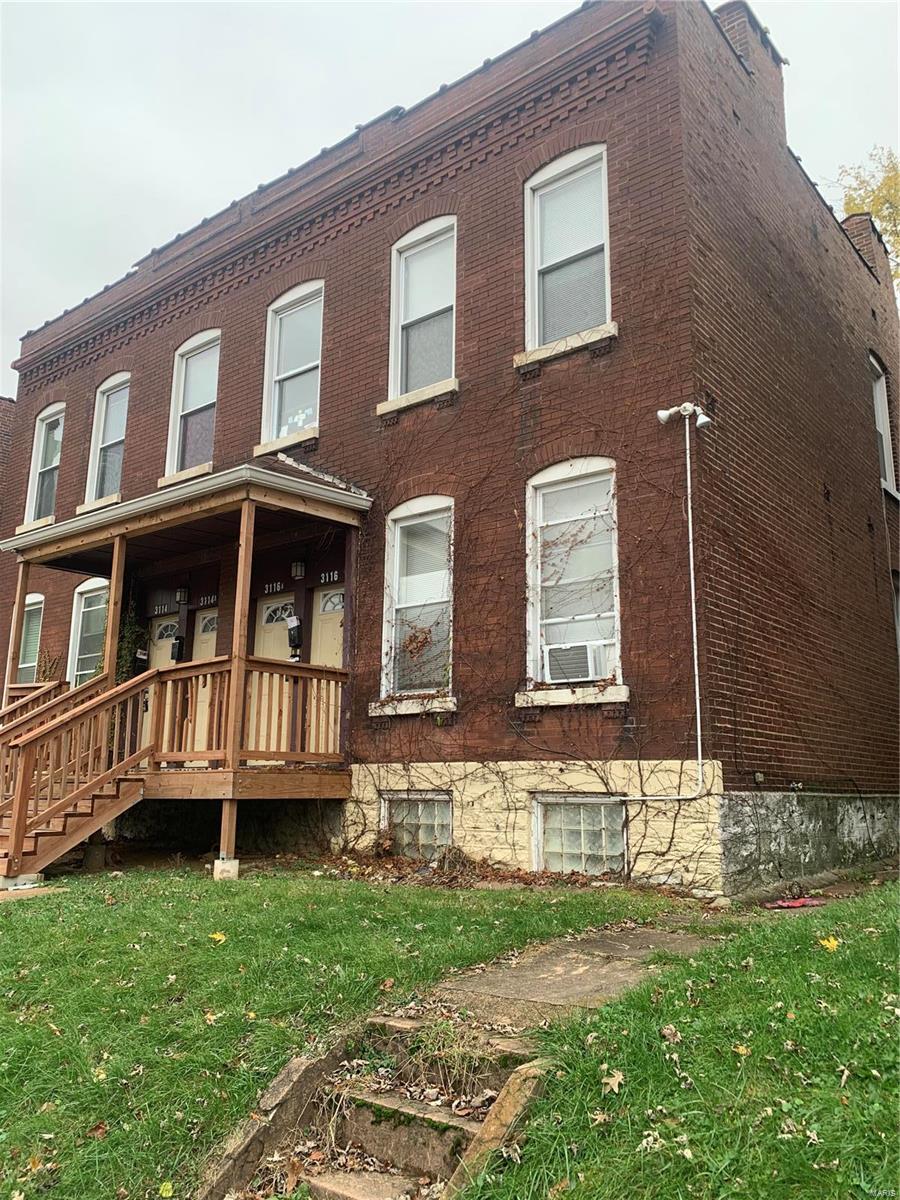 back of property with covered porch and a yard