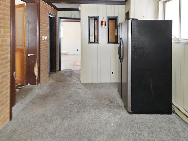 kitchen featuring a baseboard radiator, stainless steel fridge, wood walls, and beamed ceiling