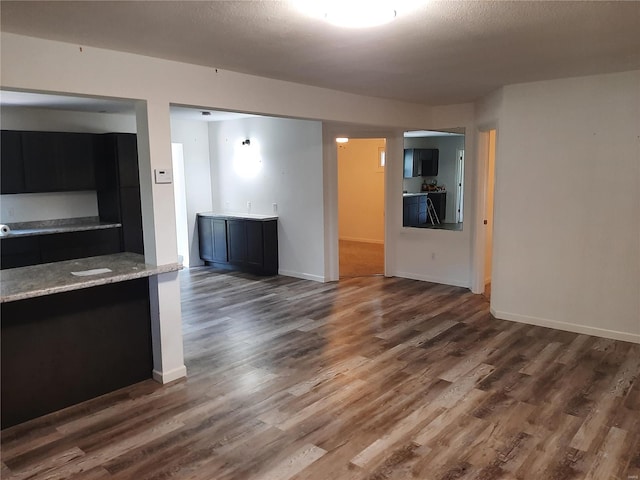 unfurnished living room featuring a textured ceiling and dark hardwood / wood-style floors