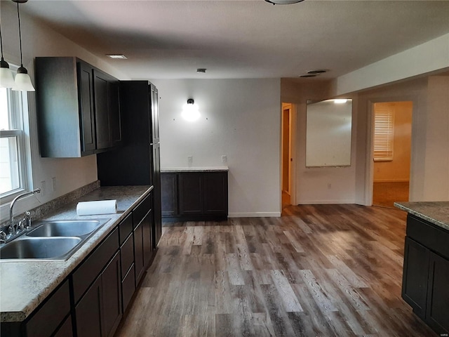 kitchen with sink, decorative light fixtures, and light hardwood / wood-style flooring