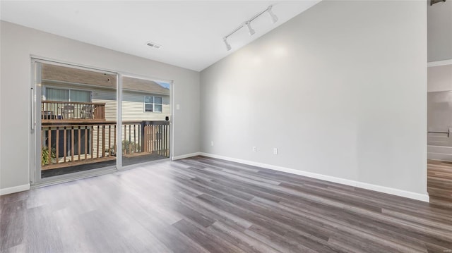 spare room featuring dark hardwood / wood-style flooring, lofted ceiling, and rail lighting