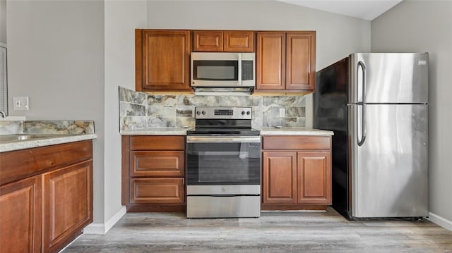 kitchen with sink, lofted ceiling, light wood-type flooring, tasteful backsplash, and appliances with stainless steel finishes