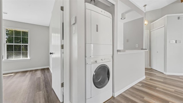 laundry room with stacked washer and clothes dryer and light wood-type flooring