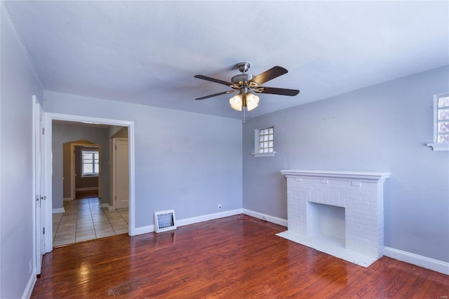 unfurnished living room with a fireplace, ceiling fan, and wood-type flooring