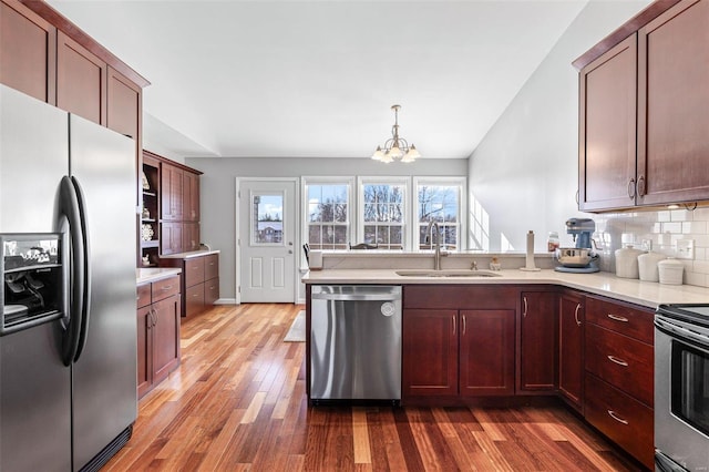 kitchen with stainless steel appliances, hanging light fixtures, dark hardwood / wood-style floors, an inviting chandelier, and tasteful backsplash