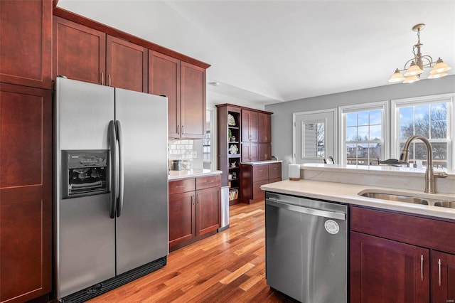 kitchen featuring sink, decorative light fixtures, backsplash, a chandelier, and appliances with stainless steel finishes