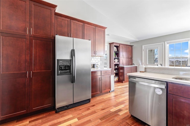 kitchen featuring lofted ceiling, backsplash, light hardwood / wood-style flooring, and appliances with stainless steel finishes