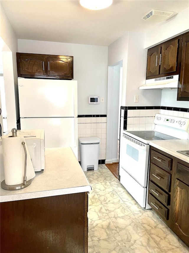 kitchen with white appliances, dark brown cabinetry, and tile walls